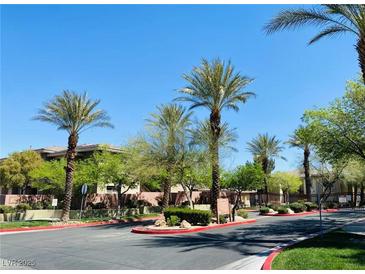Community street view with palm trees, lush landscaping, and well-maintained pathways under a bright blue sky at 908 Duckhorn Ct # 102, Las Vegas, NV 89144