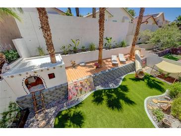 An elevated view of a backyard with a climbing wall, playground, turf, lounging area and privacy wall at 189 Andada Dr, Henderson, NV 89012