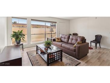 Bright living room featuring a large window, modern floors, and comfortable brown leather sofa at 2845 Loveland Dr # 3615, Las Vegas, NV 89109