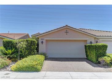 Beige one-story home with a two-car garage, desert landscaping and a tile roof under a clear blue sky at 4672 Regalo Bello St, Las Vegas, NV 89135