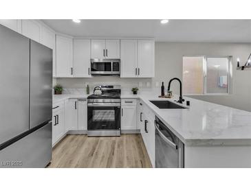 Bright kitchen features white cabinetry, stainless steel appliances, and solid surface countertops at 10373 Midnight Iris St, Las Vegas, NV 89183