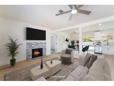 Bright living room featuring a stone fireplace, ceiling fan, and an open floorplan at 1700 Sweeney Ave, Las Vegas, NV 89104