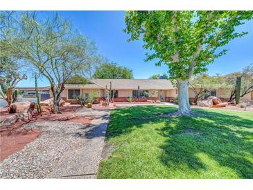 Charming home showcasing xeriscaping, mature trees, and lush green grass, perfect for enjoying outdoor desert living at 1705 Westwind Rd, Las Vegas, NV 89146