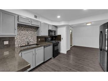 This kitchen features gray cabinets, stainless steel appliances, and a tile backsplash at 3944 Visby Ln, Las Vegas, NV 89119