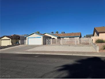 Single story home with desert landscaping, white garage door and blue roof at 725 Brick Dr, Henderson, NV 89002