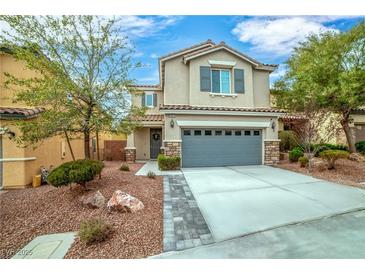 Two-story home featuring a gray two-car garage, tidy landscaping, and a charming stone-accented entrance at 10623 Kearney Mountain Ave, Las Vegas, NV 89166