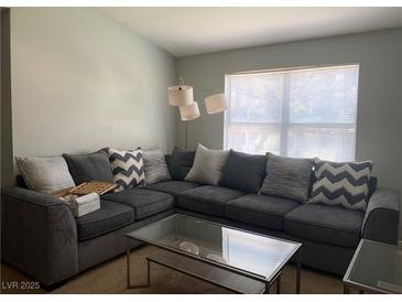 Bright living room with a large sectional sofa and a modern glass coffee table at 8101 W Flamingo Rd # 2110, Las Vegas, NV 89147