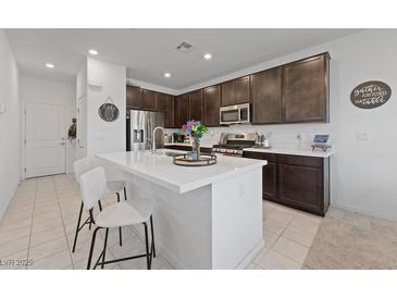 Modern kitchen featuring an island with seating, stainless steel appliances, and dark wood cabinetry at 2732 Roman Palm Rd, North Las Vegas, NV 89086