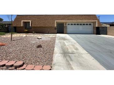 Modest home featuring a two-car garage, desert landscaping, and a long driveway at 4200 Via Vaquero Ave, Las Vegas, NV 89102