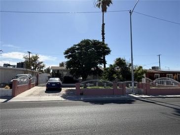 Charming single-story home featuring mature trees, a well-maintained yard, and a driveway with a parked car behind a low fence at 4567 S Nellis Blvd, Las Vegas, NV 89121