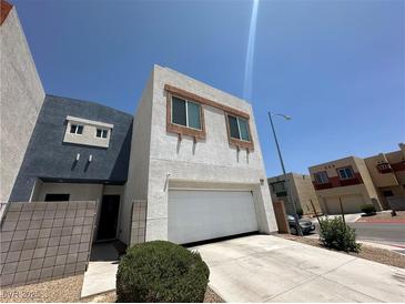 Modern two-story home features a two-car garage and neutral stucco, near a paved driveway and green shrubbery at 6450 Cinnamon Hazlenut St, North Las Vegas, NV 89084