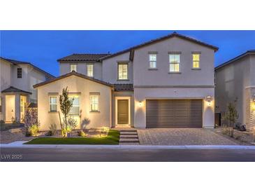 Two-story home boasting stucco exterior, a two-car garage, and a manicured front yard illuminated by landscape lighting at 8984 Rolling Pietra St, Las Vegas, NV 89166