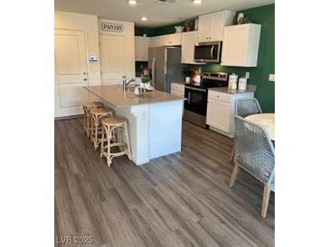 Modern kitchen with white cabinetry, stainless steel appliances, and a center island with bar seating at 1900 Arietta Vista St, Henderson, NV 89044