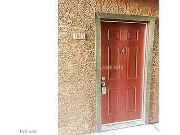 A classic six-panel front door, painted a rich maroon and secured with a modern keypad lock, welcomes visitors to home number 1045 at 2451 N Rainbow Blvd # 1045, Las Vegas, NV 89108