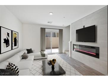 Bright living room featuring a white sofa, modern fireplace, and sliding glass door to the backyard at 2747 Tahiti Grape Way # 2, Las Vegas, NV 89183