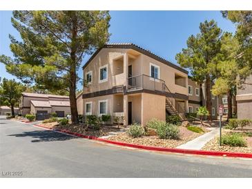 Condo exterior showing the front facade, mature landscaping, and a balcony with stairs at 5250 S Rainbow Blvd # 2101, Las Vegas, NV 89118