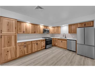 Modern kitchen with stainless steel appliances, wooden cabinets, white countertops, and light tile backsplash at 6741 Bonillo Dr, Las Vegas, NV 89103