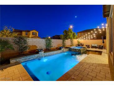 Backyard pool and spa with water features, brick pavers, landscape, and lounge area with string lights overhead at 7311 Spring Flower Ave, Las Vegas, NV 89117
