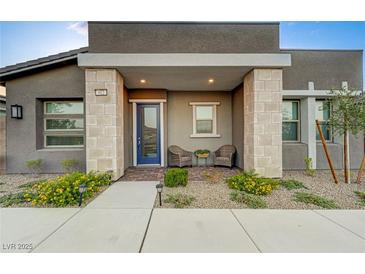 Charming front porch with blue door, stone columns, brick floor and a cozy seating area at 912 Allister Fields Ln, Las Vegas, NV 89138