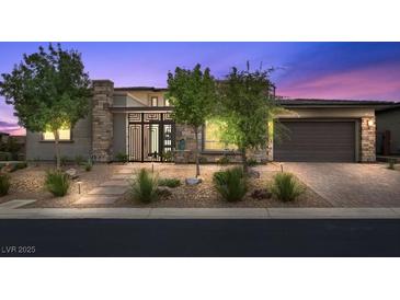 Modern home's exterior with stone accents, desert landscaping, and decorative steel front gate at 6804 Regency Stone Way, Las Vegas, NV 89148
