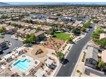 Expansive aerial view of a community featuring a pool, playground, and green spaces amidst neatly arranged homes at 4351 Hera Temple Ave, North Las Vegas, NV 89031