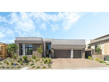 Modern home showcasing neutral colors, a front yard with new landscaping, and a brick driveway at 10919 Vista Altura Ave, Las Vegas, NV 89135