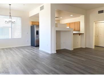 Bright living room featuring modern gray wood-look floors and an open floor plan to the kitchen at 23 E Agate Ave # 308, Las Vegas, NV 89123