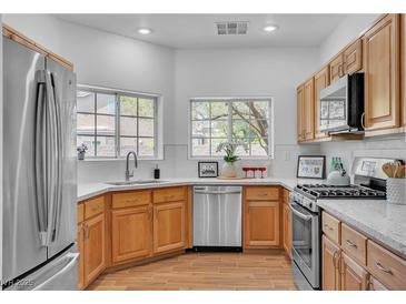 Bright kitchen features stainless steel appliances, granite countertops and wood flooring at 9047 Harbor Wind Ave, Las Vegas, NV 89178