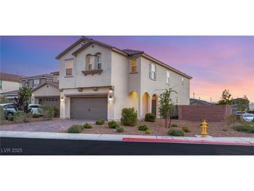 Two-story home featuring a brick driveway, two-car garage, and desert landscaping against a pink and blue sunset at 2833 Sangro Ct, Henderson, NV 89044