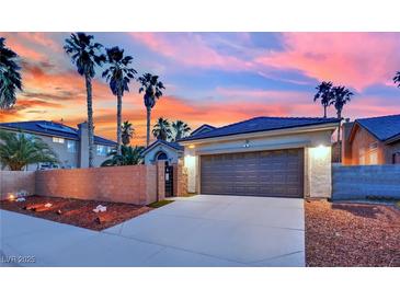 Spacious two-car garage and paved driveway under a vibrant sunset, surrounded by palm trees at 5509 Rose Thicket St, Las Vegas, NV 89130