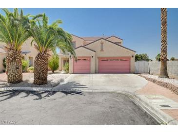 Two-story home with a two-car garage, palm trees, and desert landscaping for an appealing curb presence at 5907 Zawawi Ct, Las Vegas, NV 89110