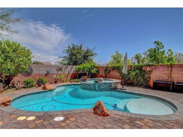 Beautiful backyard pool featuring a central rock waterfall and surrounding brick patio at 10656 Hyde Corner Ave, Las Vegas, NV 89166