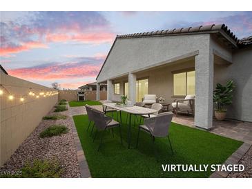 Staged covered back patio with artificial grass, string lights, and dining and seating furniture at 717 Monroe Hill Pl, Henderson, NV 89011
