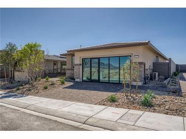 Modern single-story home featuring desert landscaping, brick drive, and sliding glass doors at 9357 Aria Ridge Ave, Las Vegas, NV 89143