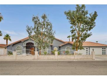 Charming single-story home showcasing a decorative iron gate, tile roof, and manicured landscaping at 1970 Del Font Ct, Las Vegas, NV 89117