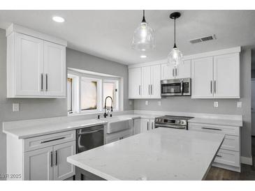 Modern kitchen featuring white cabinets, quartz countertops, stainless appliances, and stylish pendant lighting at 7060 W Rome Blvd, Las Vegas, NV 89131