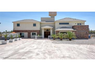 Elegant stucco home featuring stone accents, double-door entryway, and desert landscaping at 7590 Rancho Destino Rd, Las Vegas, NV 89123