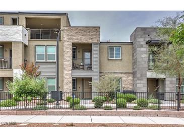 Modern multi-level townhome with stone and siding, showcasing a manicured front yard and wrought iron fence at 1120 Tektite Ave, Henderson, NV 89011