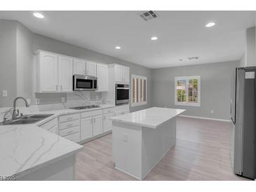 Bright, open kitchen features white cabinets, stone countertops, and stainless steel appliances at 2144 Mountain City St, Henderson, NV 89052