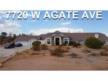 Expansive single-story home with desert landscaping, multiple-car garage, and grand entrance, bathed in natural light at 7720 W Agate Ave, Las Vegas, NV 89113