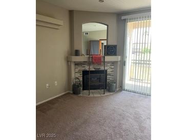 Spacious living room with a decorative fireplace and natural light streaming through the sliding glass door at 1830 N Buffalo Dr # 2021, Las Vegas, NV 89128