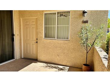 Inviting entrance with a beige door, window, and decorative tree adding charm to the exterior of the home at 7163 S Durango Dr # 113, Las Vegas, NV 89113