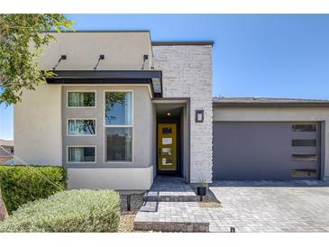 Contemporary home featuring stone accents, a yellow front door and a two-car garage at 9617 Sard Ln, Las Vegas, NV 89143