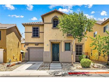 Two-story home featuring tan stucco, a tile roof, a well-manicured lawn, and an attached garage at 11894 Snow Bank St, Las Vegas, NV 89183