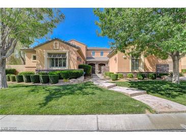 Charming two-story home with beautifully landscaped front yard and walkway leading to gated entrance at 16 Mallard Creek Trl, Henderson, NV 89052