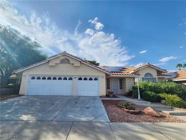Charming single-story home with a three-car garage, well-maintained landscaping and a light-colored exterior at 8220 Desert Beach Dr, Las Vegas, NV 89128