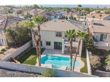 Beautiful backyard pool with putting green, palm trees, covered patio, and a white stucco home at 1811 Country Meadows Dr, Henderson, NV 89012