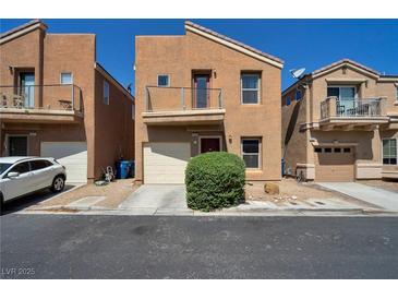 Two-story home with tan stucco, balcony, and front yard landscaping at 9443 Hot Breeze St, Las Vegas, NV 89178