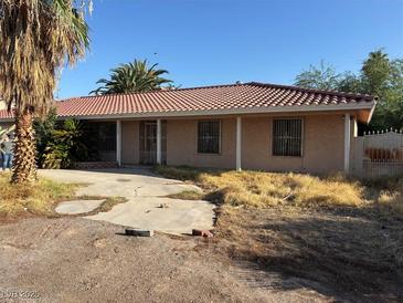 Single-story home with a red tile roof, beige stucco exterior, and front yard with desert landscaping at 4928 E Philadelphia Ave, Las Vegas, NV 89104