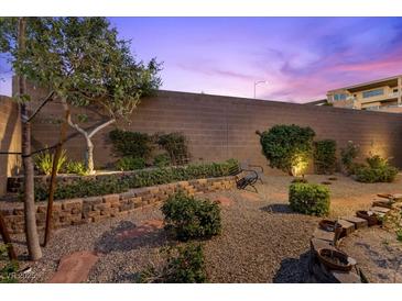 Backyard featuring a stone bench, gravel, and lush green landscaping against a block wall at 816 Stannard Ct, Henderson, NV 89052